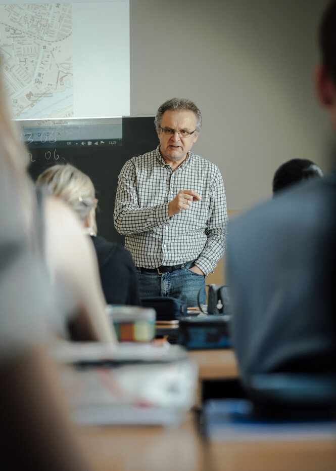 Der Lehrer Wolfgang Rall im karrierten Hemd spricht zu der Klasse