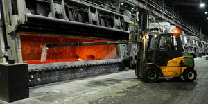 Mit einem großen Schöpflöffel wird das flüssige Aluminium in der Produktionshalle durchgerührt