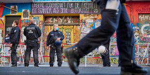 Polizisten stehen vor dem bunt belamten Hauseingang der Rigaer 94