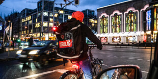 Ein Fahrradkurier von Gorillas an einer Ampel in Berlin Mitte