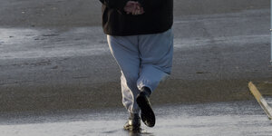 In einer grauen Jogginghose geht ein Besucher über den Anleger von Schlüttsiel an der Nordsee.