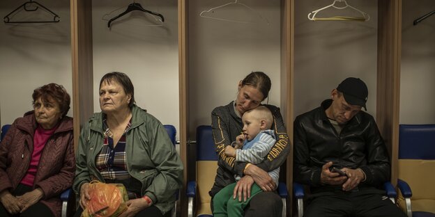 Eine geflüchtete Familie aus der Region Donezk hören einem Geiger in Lemberg in einem Schutzraum zu