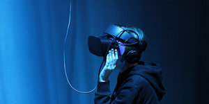 Mensch mit VR-Brille im blauem Raum
