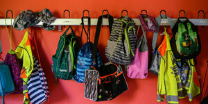 Jacken und Taschen hängen in einer Grundschule an einer Garderobe