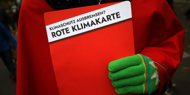 Hand hält große rote Karte mit Aufschrift "Klimaschutz ausbremsen? Rote Klimakarte"