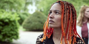 Eine Women of Color mit roten Haaren guckt nach oben