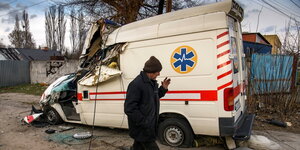 Ein Mann läuft vor einem zerstörten Krankenwagen vorbei