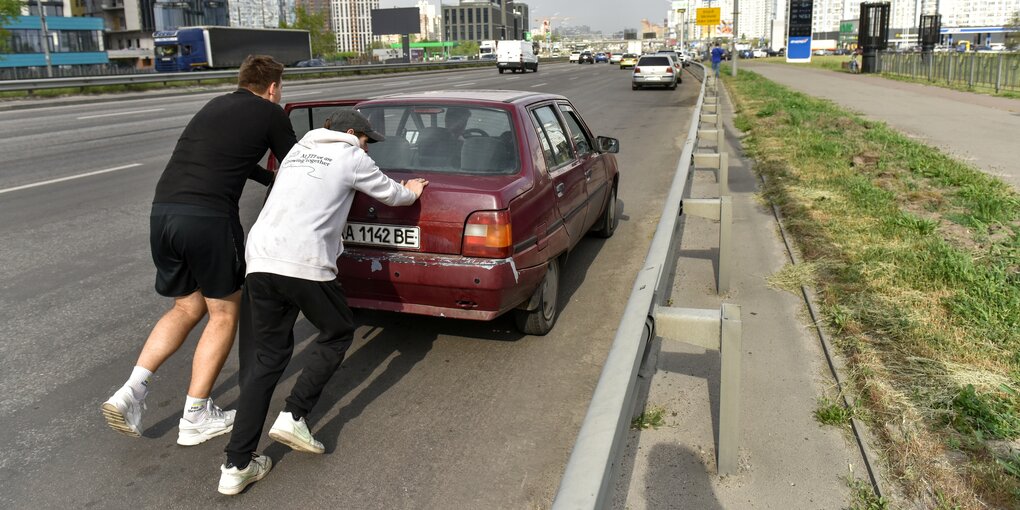 Zwei Männer schieben ein Auto an