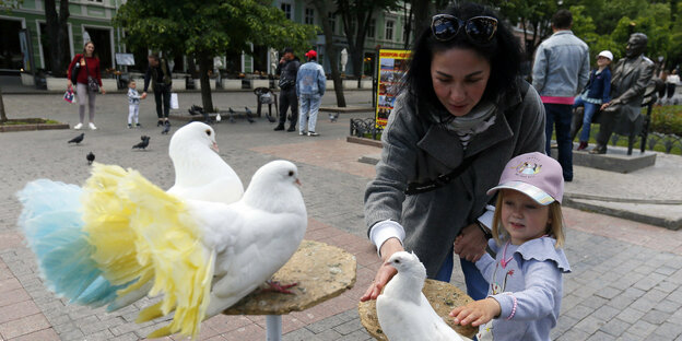 Eine Frau und ein kleines Mädchen schauen schauen sich Tauben an.