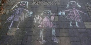 Kreidezeichnung dreier Mädchen auf Asphalt.