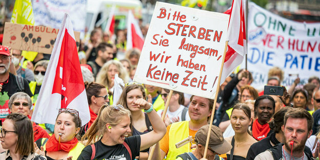 Teilnehmende einer Demo in Düsseldorf halten ein Schild hoch auf dem steht: "Bitte sterben Sie langsam, wir haben keine Zeit"