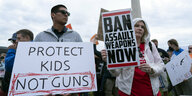 Ein Mann und eine Frau halten vor dem Washington Monument Schilder mit Forderungen nach schärferem Waffenrecht hoch