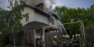 Feuerwehrleute löschen ein Haus im Grünen