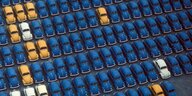 VW "Käfer" verschiedener Farben und Ausführungen stehen in enger Formation auf einem Parkplatz