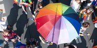 Menschen unter einem Schirm in den Farben des Regenbogens
