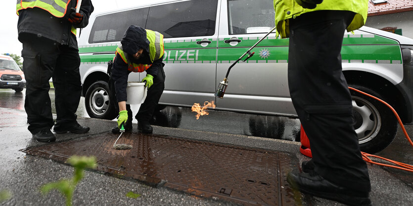 Polizisten versiegeln einen Kanaldeckel