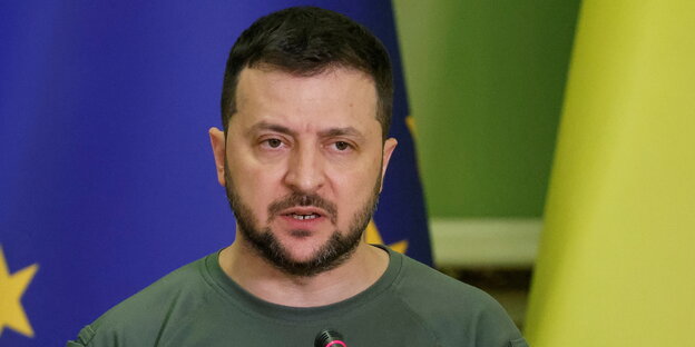 Wolodimir Selenski spricht in ein Mikrofon vor einer EU-Flagge Wolodimir Selenski spricht in ein Mikrofon vor einer EU-Flagge