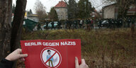 Ein Protestplakat mit einer durchgestrichenen Hitler-Figur wird in Richtung eines Naziaufmarsches gehalten