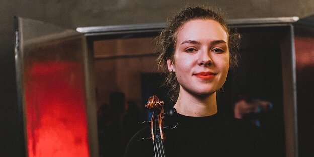 eine Portraitaufnahme von Viktoria Mendzhul mit einem Streichinstrument in der Hand.