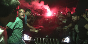 Fußballfans mit Feuerwerk vor einem Auto