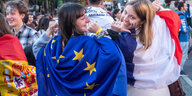 Personen freuen sich mit umgehangener Europaflagge.