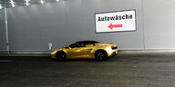 Goldenes Auto vor einer Waschanlage.