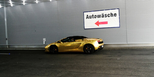 Golden car in front of a car wash.
