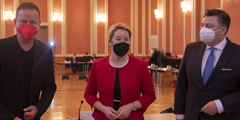 Klaus Lederer, Franziska Giffey und Andreas Geisel stehen zusammen in einem großen Saal