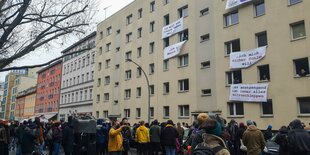 Zahlreiche Menschen stehen vor den beigen Häuserblocken der Habersaathstraße, an den Fenstern hängen Transparente