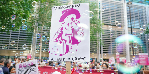 Auf einem Demonstrationsplakat steht "Migration ist kein Verbrechen" auf englisch