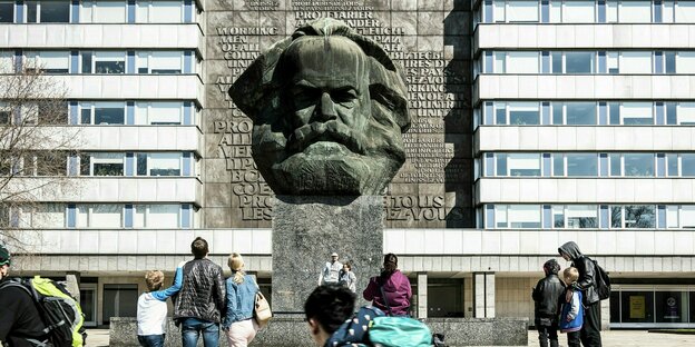 Menschen stehen vor einem Karl-Marx-Denkmal
