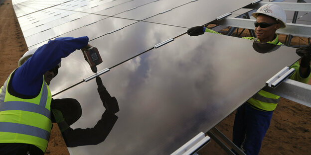 Zwei Personen installieren ein Solarmodul.