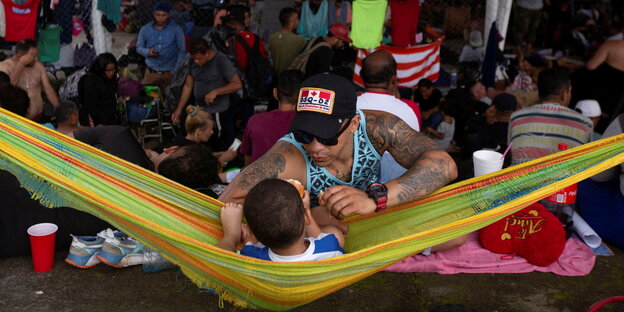 Ein Vater, der mit seinem Sohn spielt, an der Grenze zwischen Mexiko und USA