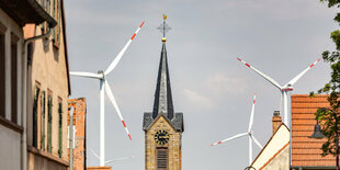 Windräder neben Kirchturm.