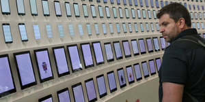 Ein Mann steht vor einer Wand mit vielen Tablet-Computern