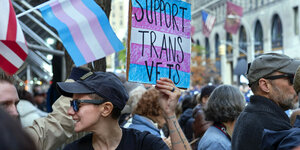 Eine Person hält ein Schild hoch, auf dem Support Trans Vets steht