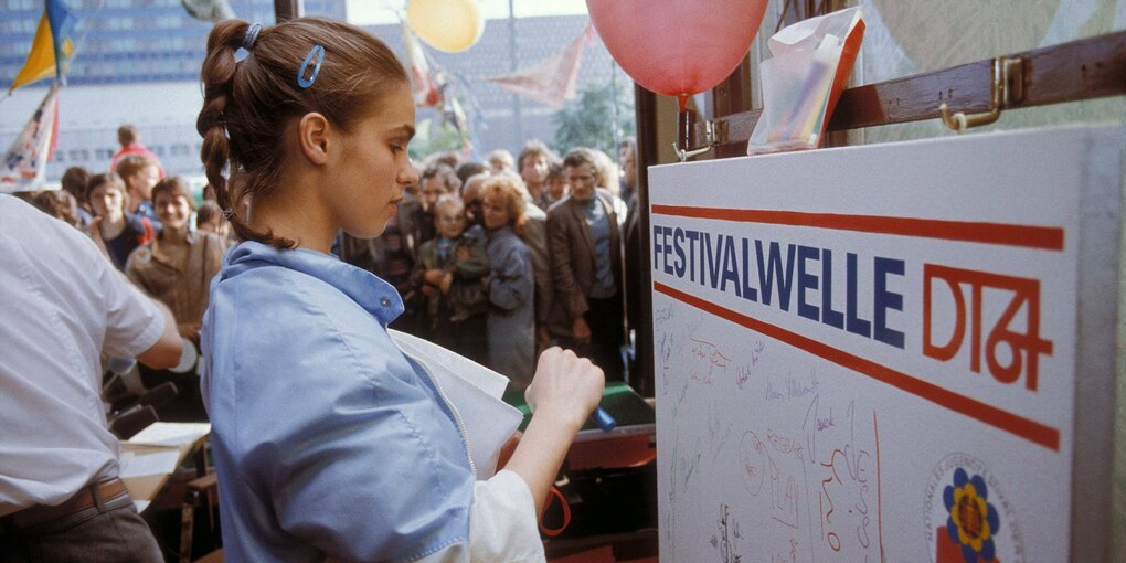 Eine junge Fraue schaut auf eine Tafel und hält einen Stift in der Hand