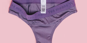 Eine lila Unterhose, in die unter dem normalen Kleidungszettel ein QR-Code eingenäht ist, auf dem Bund steht "Yes means Yes"