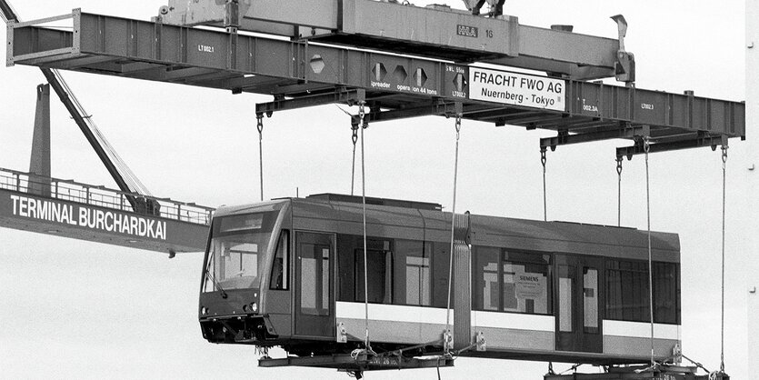 Eine Straßenbahn schwebt an einem Kran in der Luft