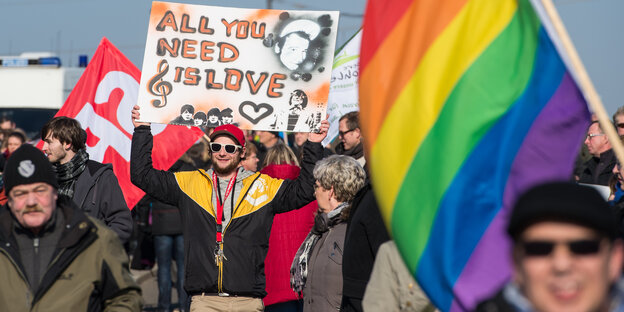 Menschen demonstrieren mit einer Regenbogenfahne gegen einen rechten Aufmarsch