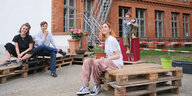 Vier Menschen sitzen in Berliner Hinterhof auf Eutropaletten