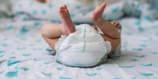 Ein Baby liegt auf einer Wickelkommode, im Fokus ist die Windel