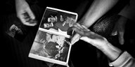 Schwarz-weiß Bild von Händen, die zwei Fotos von Männern halten