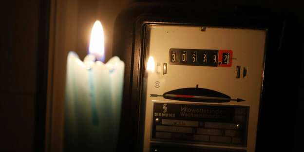 Ein Stromzähler, beleuchtet von einer Kerze