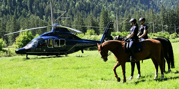 Zwei Polizistinnen reiten an einem Hubschrauber der Bundespolizei vorbei