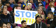Eine weinende Frau im Fussballstadionm it einem Schild: Stop Putin