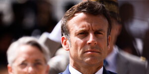 Macron nimmt mit ernstem Blick an einer Parade teil