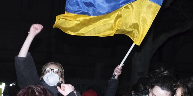 Demo vor der russischen Botschaft in Berlin am 22. Februar 2022, kurz vor Kriegsbeginn, ein junger Mensch mit Maske schwingt eine Ukraine-Flagge
