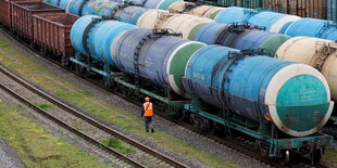 Ein Bahnangestälter läuft an Güterzügenvorbei