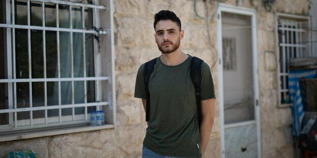 Der palästinensische Autor Mohammed El-Kurd steht vor einem Haus